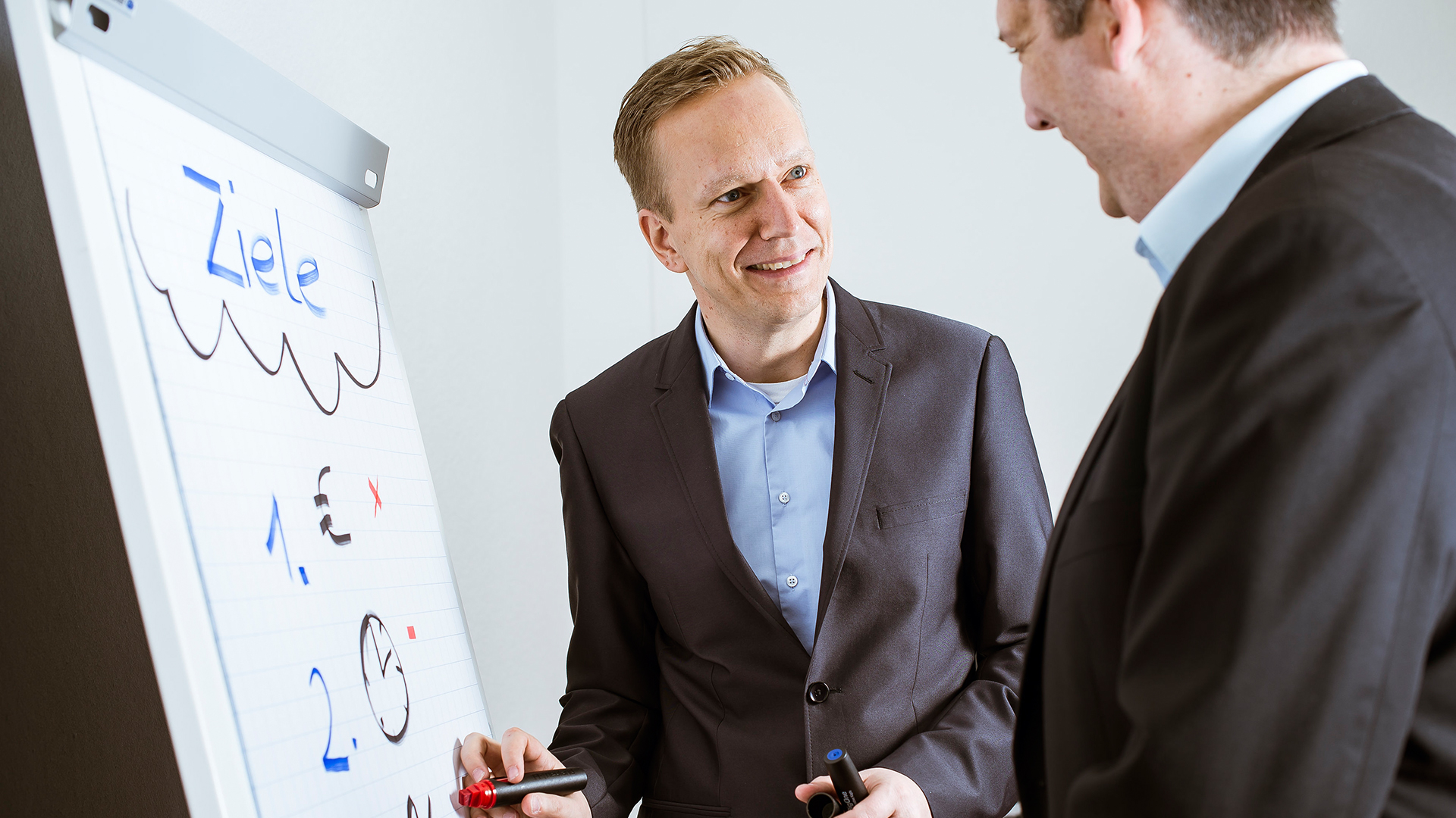 Zwei Coaches im Gespräch vor einem Flipchart